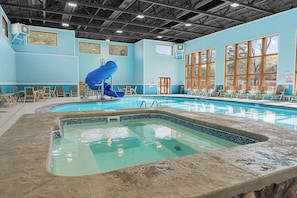 Ein Hallenbad mit blauer Rutsche, Sitzgelegenheiten und großen Fenstern.