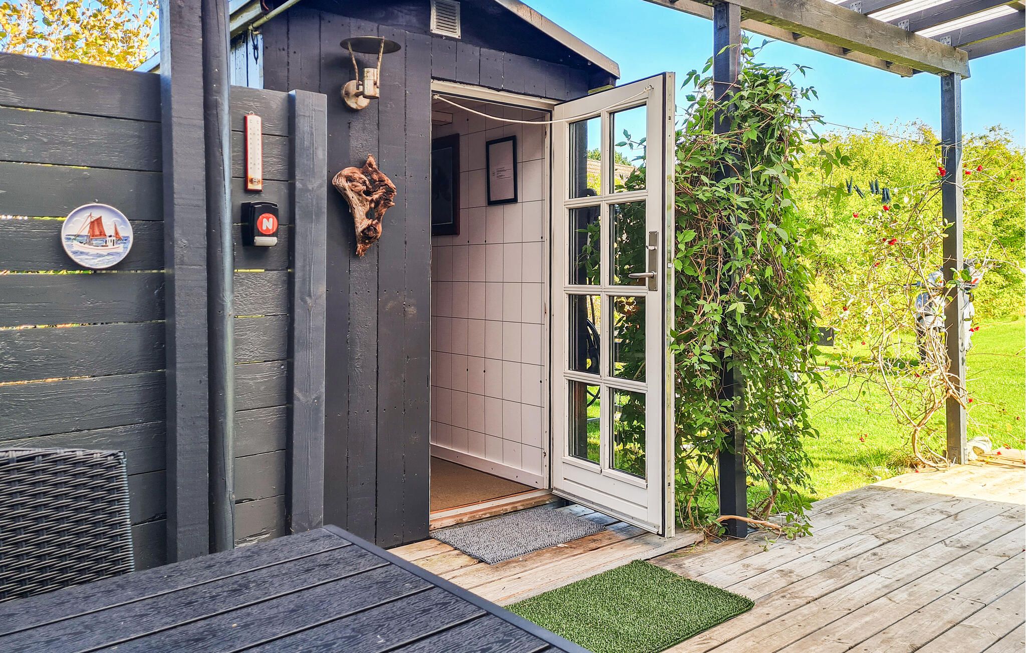 Een houten terras met een deur die leidt naar een kamer met een raam.