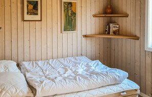 Ein Zimmer mit einem Bett, zwei gerahmten Kunstwerken und einem Bücherregal.