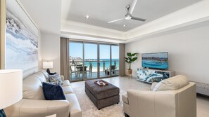 A modern living room with a sofa, ottoman, and a television. - Two 703 : The Coastal Gem (Puerto Peñasco)