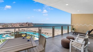 Uma varanda com vista para uma praia e um complexo de piscinas.