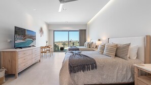 Een moderne slaapkamer met een groot bed, een televisie en uitzicht op een stadsgezicht.
