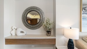 Ein Badezimmer-Waschtisch mit rundem Spiegel, einer Topfpflanze und einer Lampe.