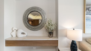 Ein Badezimmer-Waschtisch mit rundem Spiegel, einer Topfpflanze und einer Lampe.