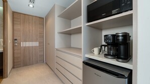 Et moderne køkken med indbygget mikroovn, kaffemaskine og køleskab.