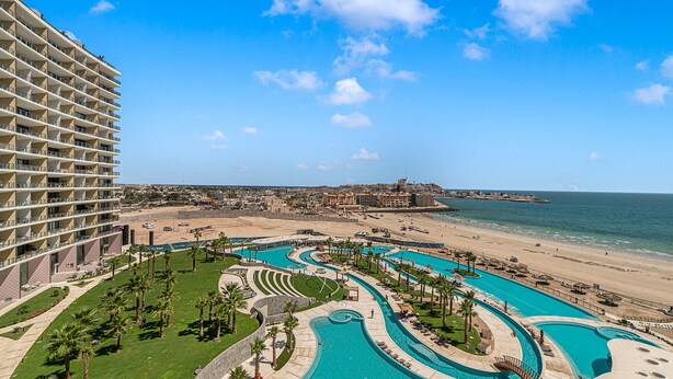 En resort med flere swimmingpools, en strand og en stor hotelbygning.