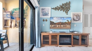 A room with a large window, a wooden cabinet, and a beach-themed wall art. - Oceanfront 2BR Condo at Princesa Resort with Stunning Sea of Cortez Views (Puerto Peñasco)