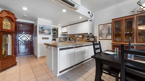 A kitchen with a central island, white cabinets, and a wooden door with a diamond pattern. - Oceanfront 2BR Condo at Princesa Resort with Stunning Sea of Cortez Views (Puerto Peñasco)