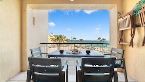 A balcony with a table and chairs, overlooking a beach and ocean. - Oceanfront 2BR Condo at Princesa Resort with Stunning Sea of Cortez Views (Puerto Peñasco)