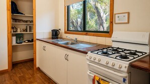 A compact kitchen with a gas stove, a sink, and a window overlooking trees. - Yelverton Brook - Fern Studio (Metricup)