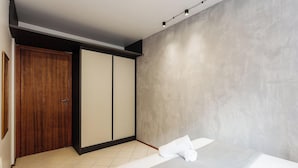 A room with a sliding door, a bed with a white mattress and a rolled-up white towel, and a textured wall. - Comfortable Ap 80m Praia dos Ingleses Amc0202 (Florianópolis)