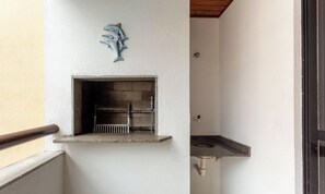 A small outdoor grill area with a stone shelf and a metal rack. - Comfortable Ap 80m Praia dos Ingleses Amc0202 (Florianópolis)