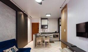 Eine moderne Küche mit Fernseher, einem Essbereich mit Stühlen und einem blauen Sofa.