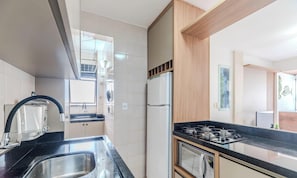 A modern kitchen with a black countertop, stainless steel sink, and a built-in stove. - Belo Cozy Apartment 4 Minutes From the sea Amc0204 (Florianópolis)