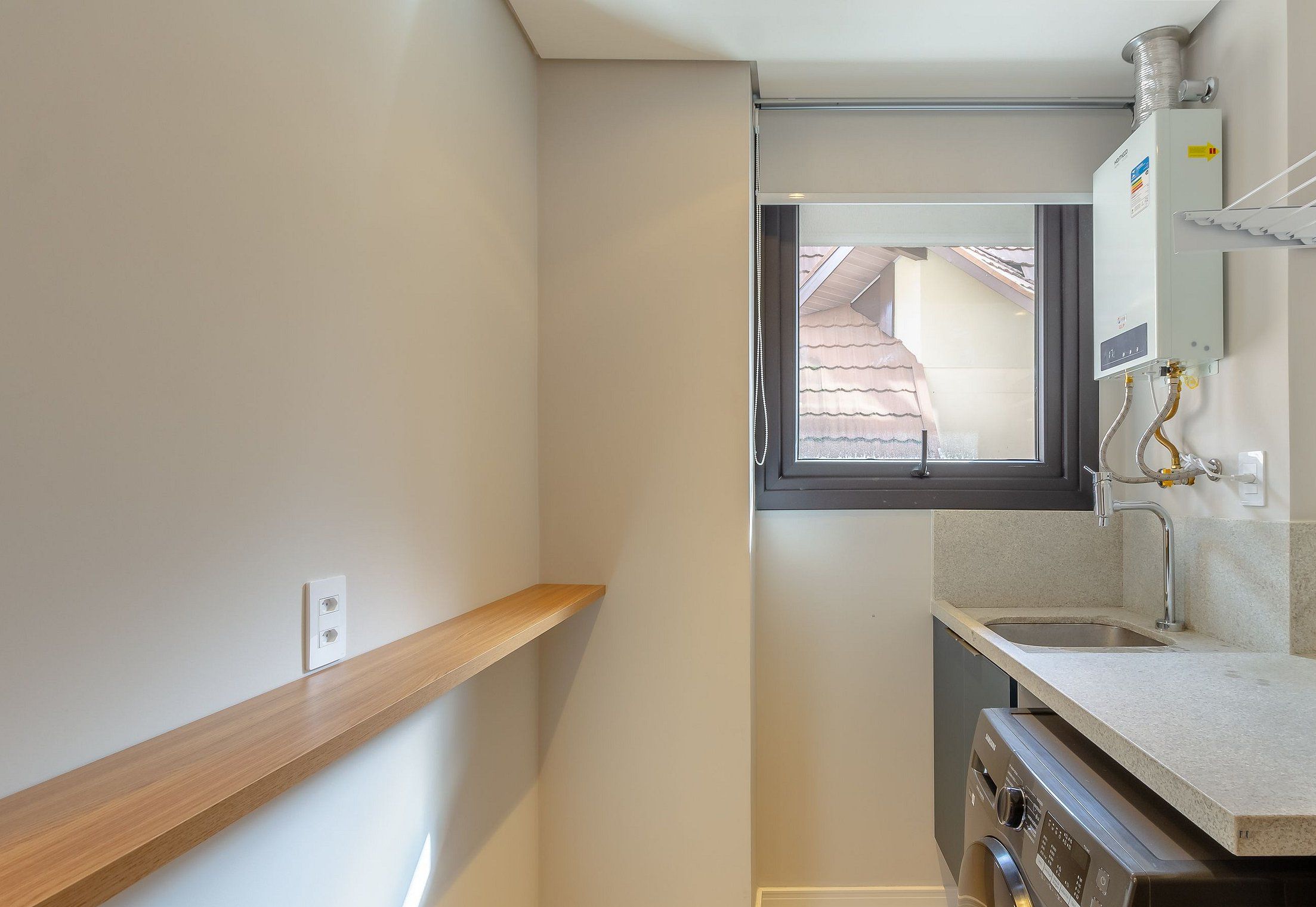Una cocina compacta con ventana, estante de madera y horno empotrado.
