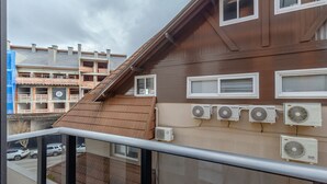 Un edificio residencial con varias unidades de aire acondicionado, un balcón con baranda de metal y vistas a edificios vecinos.