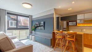 Una cocina moderna con televisión de pantalla plana, taburetes de madera y microondas integrado.