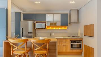 Cocina compacta con microondas, horno y un pequeño comedor con dos sillas y una mesa.