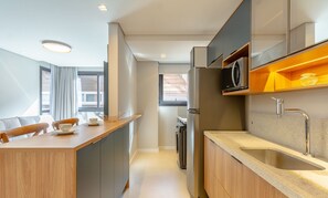 A modern kitchen with a built-in island, a microwave, and a sink. - Cozy Apartment in Downtown Gramado Dlh0302 (Gramado)