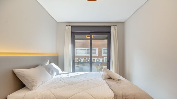 Un dormitorio con cama, cortinas y vistas a un espacio exterior con unidades de aire acondicionado.