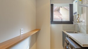 Una cocina compacta con ventana, estante de madera y horno empotrado.