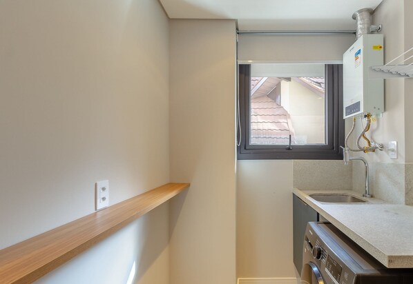 A compact kitchen with a window, a wooden shelf, and a built-in oven. - Cozy Apartment in Downtown Gramado Dlh0302 (Gramado)