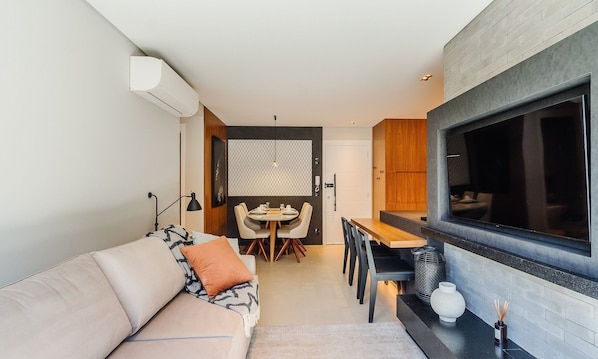 A compact living space with a sofa, dining table, and a large window. - Apartment in the Center Near Rua Coberta Dlh0303 (Gramado)