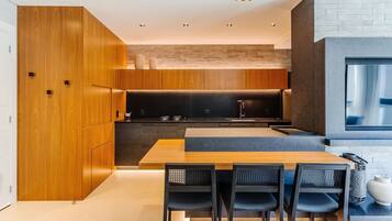 Una cocina moderna con armarios de madera, encimera negra y zona de comedor con cuatro sillas.
