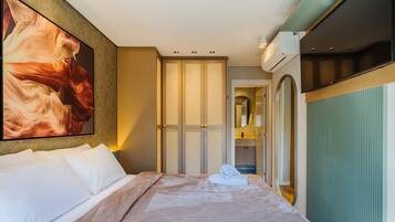Una habitación de hotel con una cama, un cuadro grande, un armario, un espejo y un equipo de aire acondicionado.