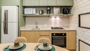 Eine kompakte Küche mit Kühlschrank, Mikrowelle, Kaffeemaschine und Backofen.