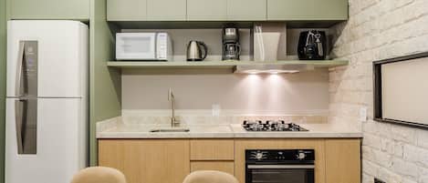 A compact kitchen with a refrigerator, microwave, coffee maker, and oven.