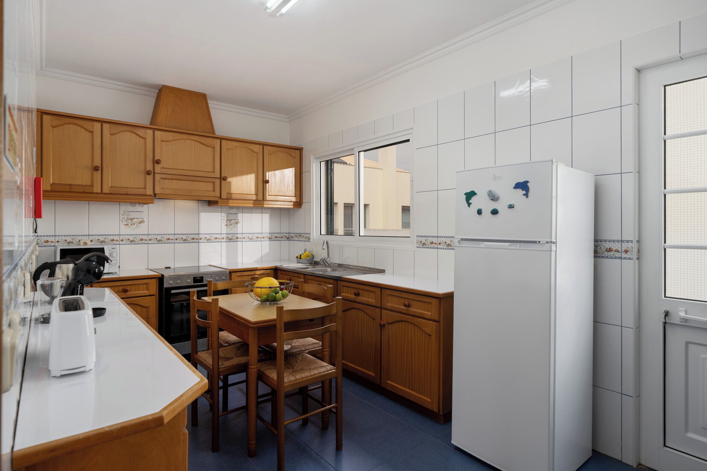 Eine Küche mit Holzausstattung, einem weißen Kühlschrank und einem Esstisch mit Stühlen.
