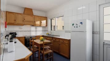 A kitchen with wooden cabinets, a white refrigerator, and a dining table with chairs.