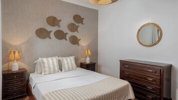 Un dormitorio con una cama, dos mesitas de noche, un aparador, un espejo en la pared y decoración mural.