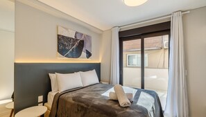A hotel room with a bed, a small table, a wall-mounted artwork, and a window with curtains. - Beautiful Apartment in Gramado Dlh0201 (Gramado)