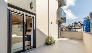 A modern hotel room with a sliding glass door, a small balcony, and a view of neighboring houses. - Beautiful Apartment in Gramado Dlh0201 (Gramado)