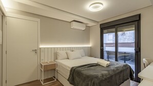 Ein Schlafzimmer mit einem Bett, einem Nachttisch und einem Fenster mit Blick nach draußen.