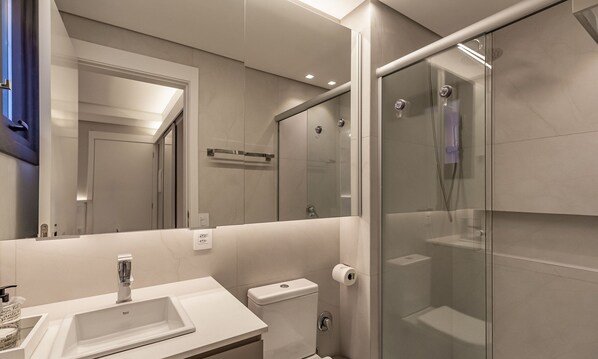 A modern bathroom with a glass shower enclosure, a sink with a mirror, and a toilet. - Modern Apartment in the Center of Gramado Dlh0206 (Gramado)