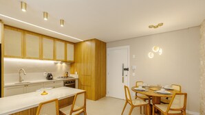 Een moderne keuken met een centraal eiland, houten kastjes en een eethoek met een ronde tafel en stoelen.