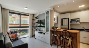 A modern kitchen with a bar area, built-in appliances, and a large window offering a view of the outdoors. - Charming Apartment in Gramado Dlh0205 (Gramado)