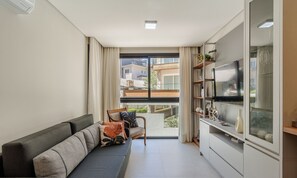 A modern living room with a sofa, a chair, and a TV. - Charming Apartment in Gramado Dlh0205 (Gramado)