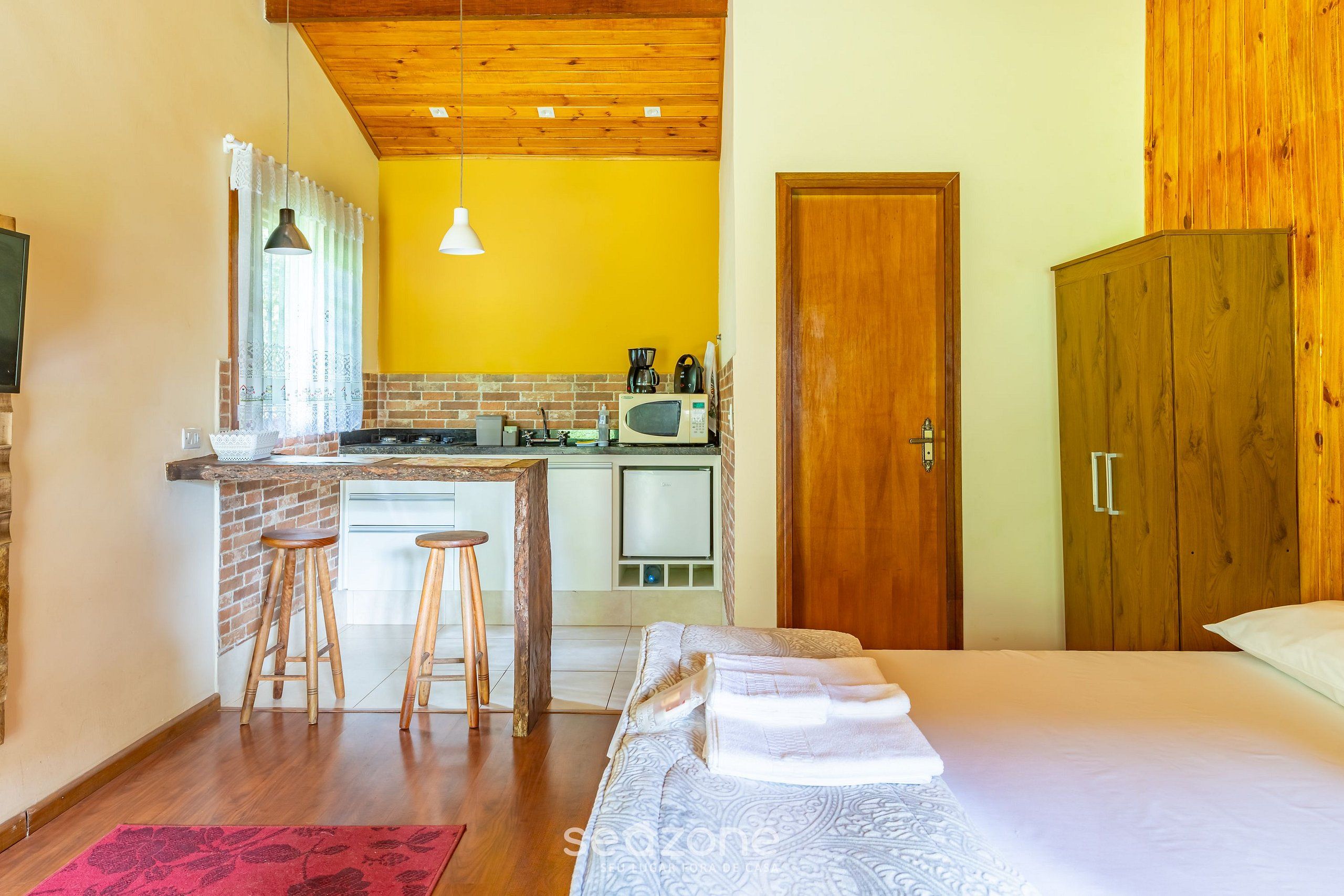 Habitación pequeña con kitchenette, cama y armario.