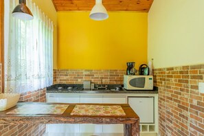 Een compacte keuken met een tegel achterwand, een magnetron, waterkoker en fornuis.