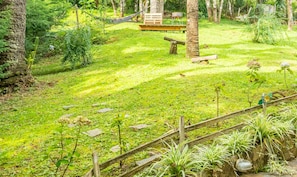 A lush garden with a hammock, wooden bench, and a stone pathway. - Relaxing Chalet Campos do Jordao-sp Rds002 (Campos do Jordão)