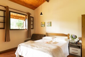 A bedroom with a bed, a nightstand, a window with curtains, and a wooden ceiling. - Relaxing Chalet Campos do Jordao-sp Rds002 (Campos do Jordão)