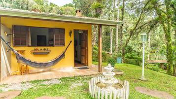 A yellow house with a hammock, a fountain, and a garden.