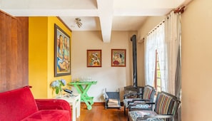 A living room with a red sofa, a green table with a vase of flowers, and a black fireplace. - Encantador Chalet en Campos do Jordao-sp Rds001 (Campos do Jordão)