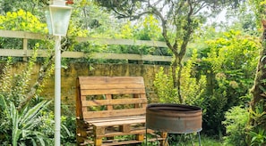 A wooden bench and a metal pot in a lush garden setting. - Encantador Chalet en Campos do Jordao-sp Rds001 (Campos do Jordão)