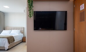 Un dormitorio con cama, televisor montado en la pared y una puerta con letrero de prohibido fumar.