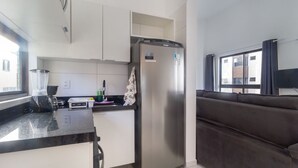 A modern kitchen with a built-in refrigerator, a coffee machine, and a window providing natural light. - Modern Beachside Comfort in Boa Viagem - Iaa1004 (Recife)